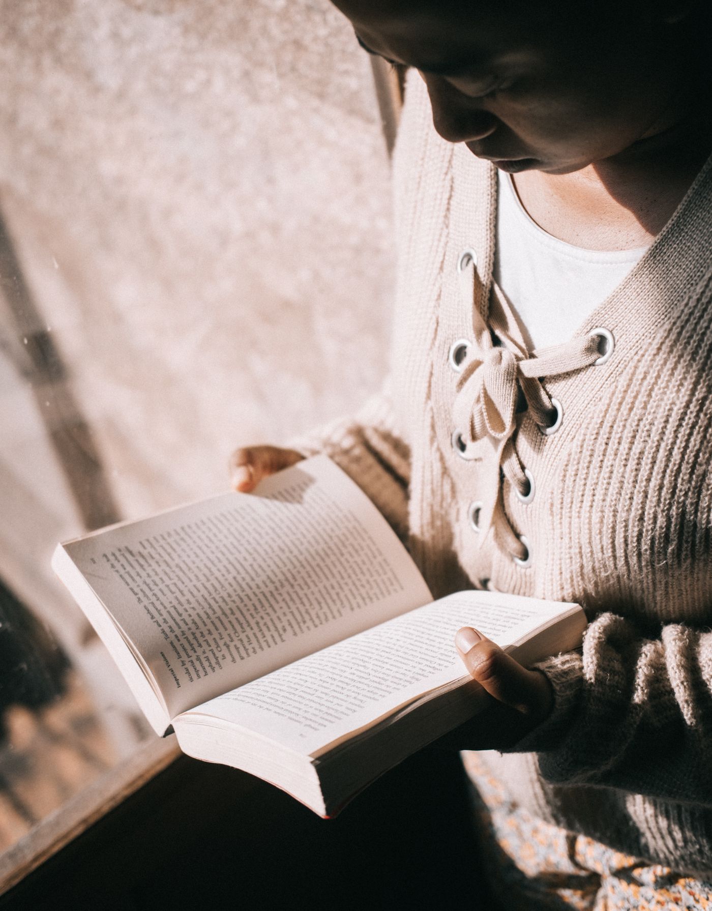 Person relaxing with an open book in a cozy knit sweater